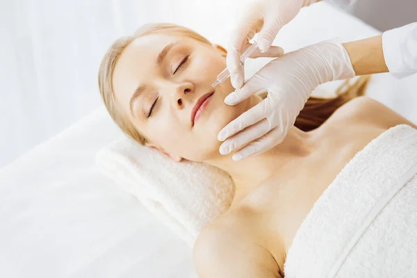 Lekarz kosmetyk robi zabieg kosmetyczny ze strzykawką dla białej kobiecej twarzy w pokoju synchronicznym. Medycyna i chirurgia kosmetyczna, koncepcja zastrzyków kosmetycznych — Zdjęcie stockowe