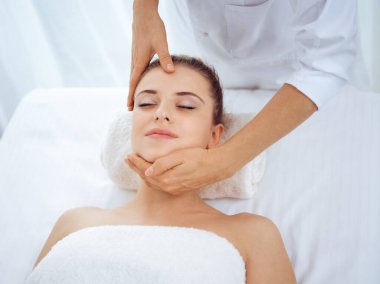 Genç ve sarışın kadın spa salonunda yüz masajından zevk alıyor. Güzellik konsepti