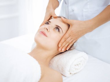 Genç ve sarışın kadın spa salonunda yüz masajından zevk alıyor. Güzellik konsepti