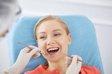 Gülümseyen beyaz kadın dişçi kliniğinde dişçi tarafından muayene ediliyor. Sağlıklı dişler ve ilaçlar, stomatoloji konsepti