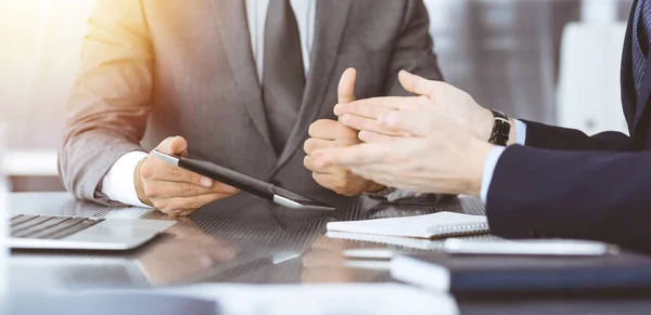 Hombre de negocios desconocido que utiliza la computadora de la tableta y el trabajo junto con su colega mientras se sienta en el escritorio de cristal en la oficina moderna. Trabajo en equipo y concepto de asociación — Foto de Stock