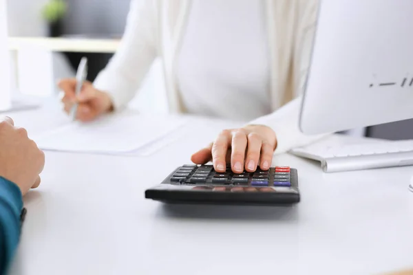 Contabilista verificando ficha financeira ou contando por calculadora de renda para a forma de imposto, mãos close-up. Mulher de negócios sentada e trabalhando com colega na mesa no escritório. Conceito de Fiscalidade e Auditoria — Fotografia de Stock