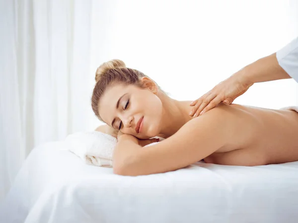 Ung och blond kvinna njuter av massage av tillbaka i spa salong. Skönhetsbegreppet — Stockfoto