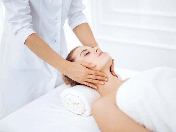 Mujer joven y rubia disfrutando de masajes faciales en el salón de spa. Concepto de belleza — Foto de Stock