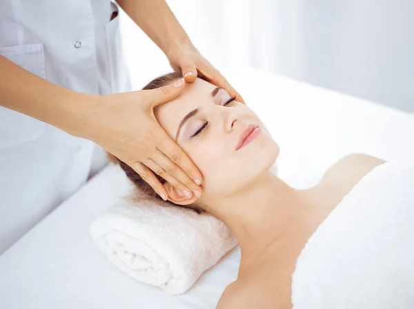 Jonge en blonde vrouw geniet van gezichtsmassage in spa salon. Schoonheidsconcept — Stockfoto