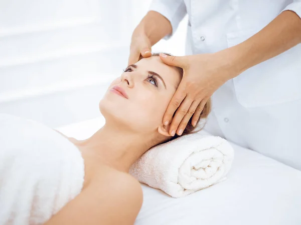 Mujer joven y rubia disfrutando de masajes faciales en el salón de spa. Concepto de belleza — Foto de Stock