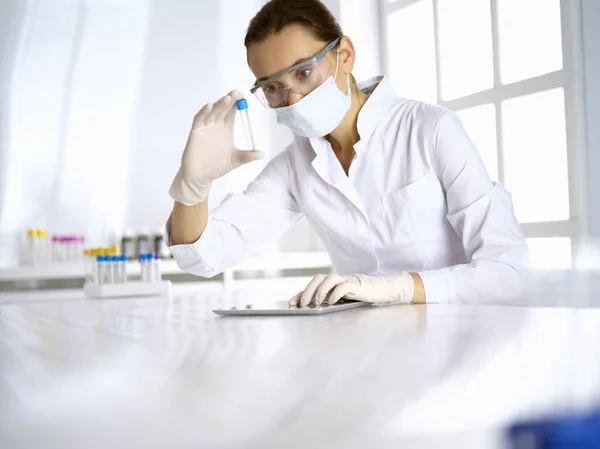 Asistente de laboratorio mujer analizando una muestra de sangre en el hospital. Medicina, salud y concepto de investigación — Foto de Stock