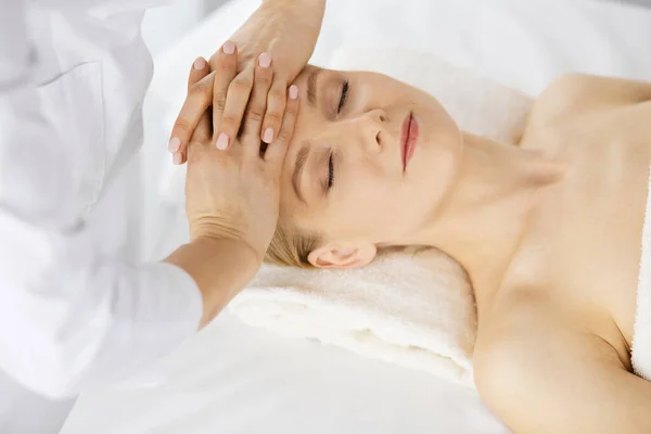 Beautiful caucasian woman enjoying facial massage with closed eyes in spa salon. Relaxing treatment in medicine and Beauty concept Royalty Free Stock Images