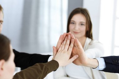 Takım çalışması yapan ve el ele tutuşan iş adamları grubu ya da modern ofiste beş kişi. Bilinmeyen işadamı ve kadınlar elleriyle daire çiziyorlar.