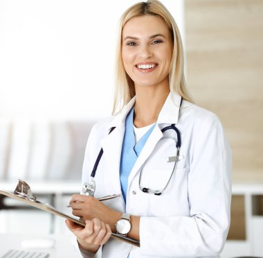 Doktor kadın, Sunny Hastanesi 'nde pano kullanırken ilaç kayıtlarını ve sınav sonuçlarını kontrol ediyor. Tıp ve sağlık hizmetleri kavramı