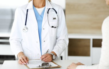 Bilinmeyen kadın doktor ve hasta hastanede. Sarışın doktor ilaç kayıtlarını ve sınav sonuçlarını kontrol ederken pano kullanıyor, yakın plan. Tıp konsepti