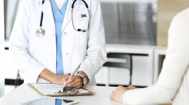 Bilinmeyen kadın doktor ve hasta hastanede. Sarışın doktor ilaç kayıtlarını ve sınav sonuçlarını kontrol ederken pano kullanıyor, yakın plan. Tıp konsepti
