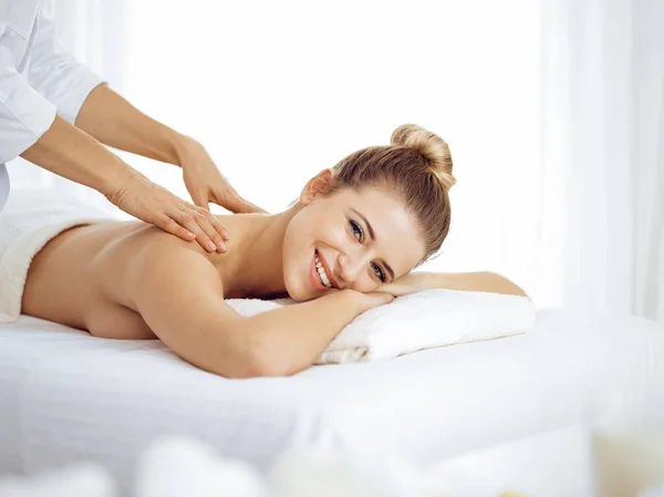 Mujer joven y rubia disfrutando del masaje de espalda en el salón de spa. Concepto de belleza — Foto de Stock