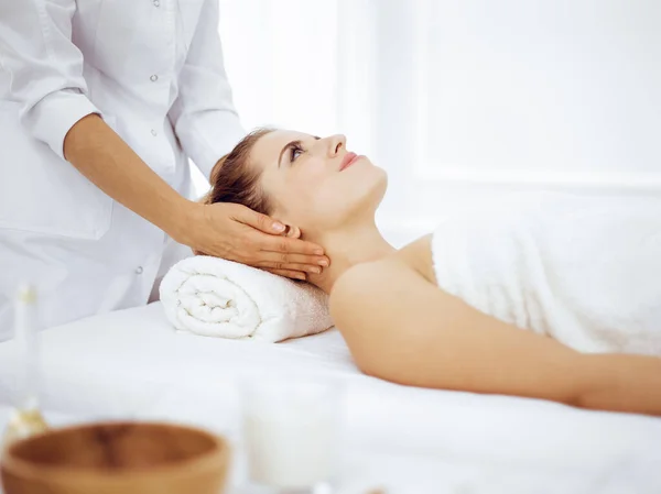 Jonge en blonde vrouw geniet van gezichtsmassage in spa salon. Schoonheidsconcept — Stockfoto