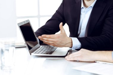 Modern ofiste birlikte çalışırken dizüstü bilgisayarı kullanan iş adamları. İş yerinde iş arkadaşı olan tanınmamış bir iş adamı ya da erkek girişimci. Takım çalışması ve ortaklık kavramı