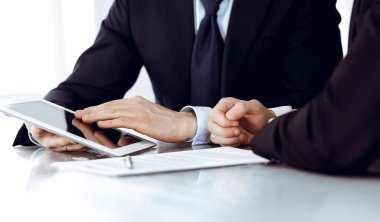 İş adamları modern ofiste çalışırken tablet bilgisayar kullanıyorlar. İş yerinde iş arkadaşı olan bilinmeyen bir iş adamı. Takım çalışması ve ortaklık kavramı