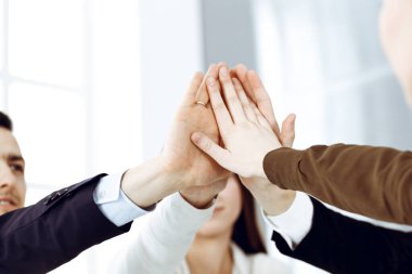 Takım çalışması yapan ve el ele tutuşan iş adamları grubu ya da modern ofiste beş kişi. Bilinmeyen işadamı ve kadınlar elleriyle daire çiziyorlar.