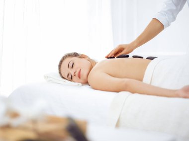 Genç ve sarışın kadın kaplıcada sıcak taşlarla tedavi görüyor. Güzellik konsepti