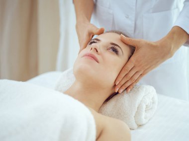 Genç ve sarışın kadın spa salonunda yüz masajından zevk alıyor. Güzellik konsepti
