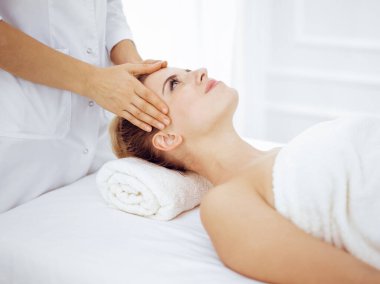 Genç ve sarışın kadın spa salonunda yüz masajından zevk alıyor. Güzellik konsepti