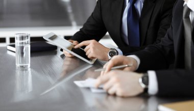 Bilinmeyen işadamları tablet bilgisayar kullanıyor ve modern ofisteki cam masada birlikte çalışıyorlar. Yakın plan. Takım çalışması ve ortaklık kavramı