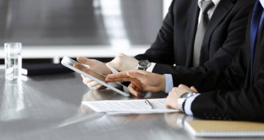 Bilinmeyen işadamları tablet bilgisayar kullanıyor ve modern ofisteki cam masada birlikte çalışıyorlar. Yakın plan. Takım çalışması ve ortaklık kavramı