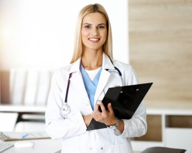 Doktor kadın, Sunny Hastanesi 'nde pano kullanırken ilaç kayıtlarını ve sınav sonuçlarını kontrol ediyor. Tıp ve sağlık hizmetleri kavramı