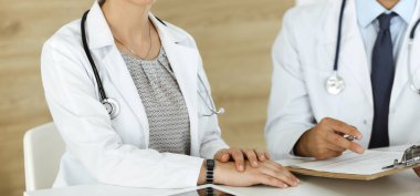 İki bilinmeyen doktor hastane ofisinde masa başında otururken tedavi sorunlarını tartışıyor, yakın plan. Tıptaki veriler