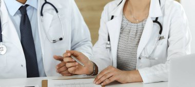 İki bilinmeyen doktor hastane ofisinde masa başında otururken tedavi sorunlarını tartışıyor, yakın plan. Tıptaki veriler