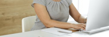Modern ofiste masa başında otururken bilgisayarla çalışan tanınmayan bir iş kadını, yakın plan. Orta yaşlı kadın avukat ya da denetçi.