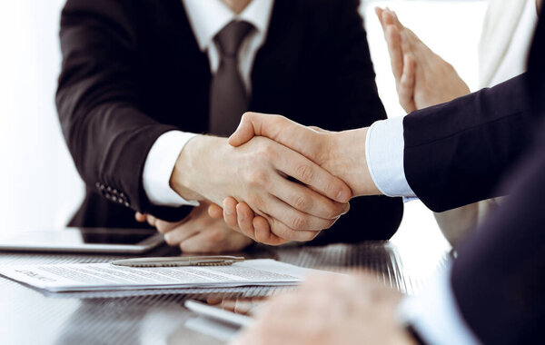 Business people shaking hands after contract signing in modern office. Teamwork, partnership and handshake concept