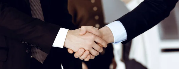 Zakenmensen schudden elkaar de hand na het tekenen van een contract terwijl ze in een modern kantoor staan. Teamwork en handdruk concept — Stockfoto