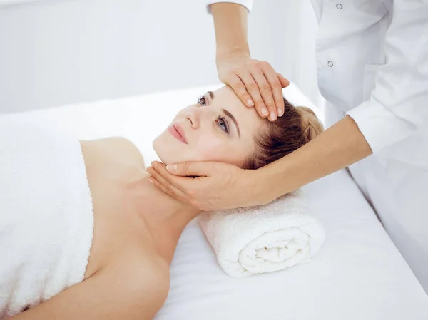 Jonge en blonde vrouw geniet van gezichtsmassage in spa salon. Schoonheidsconcept — Stockfoto