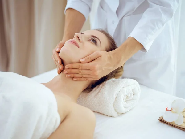 Mulher jovem e loira desfrutando de massagem facial no salão de spa. Conceito de beleza — Fotografia de Stock