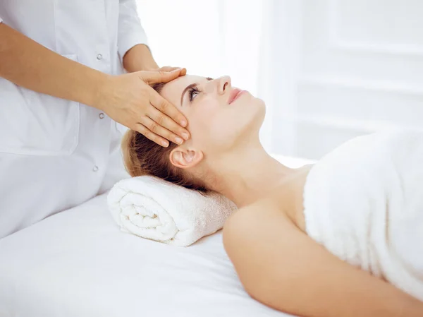 Mujer joven y rubia disfrutando de masajes faciales en el salón de spa. Concepto de belleza — Foto de Stock