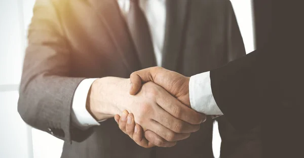 Neznámí různí obchodníci si potřásají rukama a podepisují kontrakt ve slunné kanceláři, zblízka. Koncept business handshake — Stock fotografie