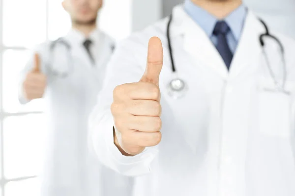 Twee mannelijke dokters staan als een team met duimen omhoog in het ziekenhuis kantoor en klaar om patiënten te helpen. Medische hulp, beste ziektebehandeling en medicijnconcept — Stockfoto