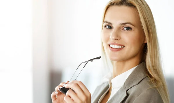 Sexy blonde business woman smiling while standing in sunny office