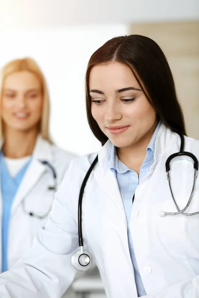 Brunette woman-doctor controls medication history records and exam results while using clipboard in sunny clinic Stock Photo