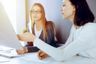 İş kadını, bayan meslektaşına sunum yaparken tablet bilgisayar ekranını işaret ediyor. Ofisteki masada çalışan bir grup iş adamı. Takım çalışması konsepti