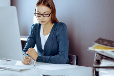 Muhasebeci mali durumu kontrol ediyor ya da vergi formları için hesap makinesi geliri ile sayıyor, eller yakın çekim. Ofisteki masada oturan ve çalışan bir iş kadını. Denetim kavramı