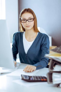 Muhasebeci mali durumu kontrol ediyor ya da vergi formları için hesap makinesi geliri ile sayıyor, eller yakın çekim. Ofisteki masada oturan ve çalışan bir iş kadını. Denetim kavramı