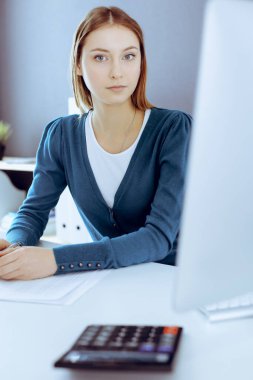 Muhasebeci mali durumu kontrol ediyor ya da vergi formları için hesap makinesi geliri ile sayıyor, eller yakın çekim. Ofisteki masada oturan ve çalışan bir iş kadını. Denetim kavramı