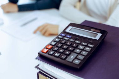 Hesap makinesi ve kağıtlar iş kadını ya da ofisteki büroda çalışan muhasebeci tarafından incelenmeyi bekliyor. İç Denetim ve vergi kavramı