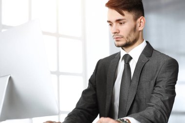 Güneşli ofiste bilgisayarla çalışan bir iş adamı. İş yerindeki erkek girişimcinin vesikalığı. İş konsepti