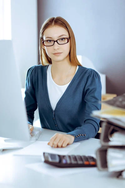 Accountant checking financial statement or counting by calculator income for tax form, hands close-up. Business woman sitting and working at the desk in office. Audit concept