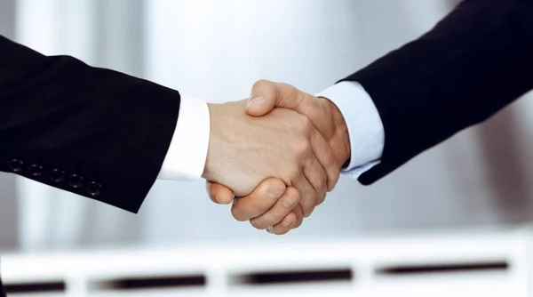 Los empresarios se dan la mano después de firmar el contrato mientras están de pie en una oficina moderna. Trabajo en equipo y concepto de apretón de manos — Foto de Stock