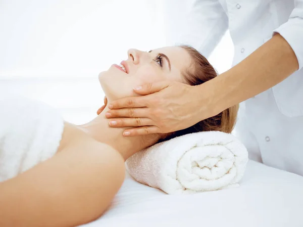Mulher jovem e loira desfrutando de massagem facial no salão de spa. Conceito de beleza — Fotografia de Stock