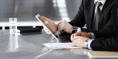 Bilinmeyen işadamları tablet bilgisayar kullanıyor ve modern ofisteki cam masada birlikte çalışıyorlar. Yakın plan. Takım çalışması ve ortaklık kavramı