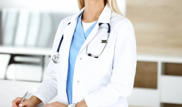 Médica desconhecida está de pé em seu local de trabalho perto de computador desktop, close-up. Conceito de medicina — Fotografia de Stock